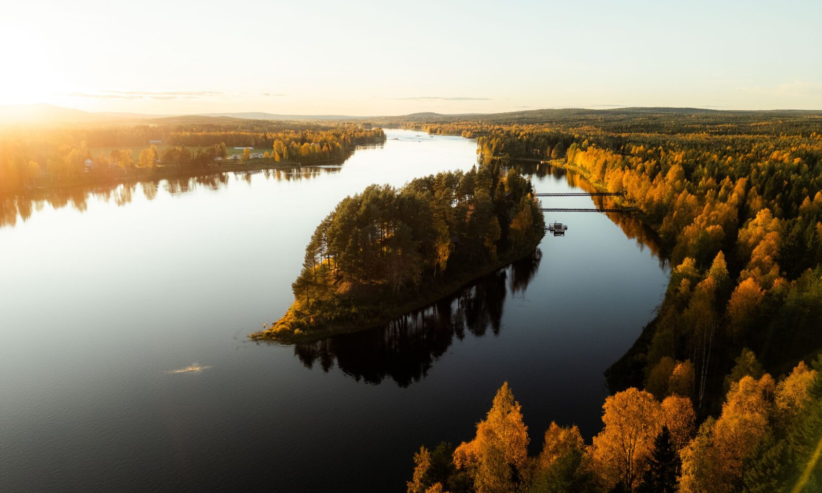 Aerial view of Aino Private Island surrounded by calm water and golden ruska forest in Rovaniemi, Finnish Lapland.