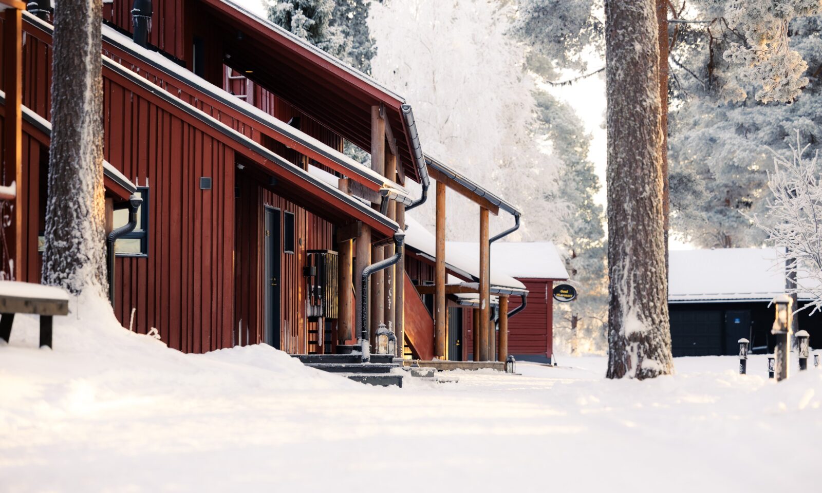 Snow-covered wooden buildings at Aino Private Island surrounded by pine forest in Rovaniemi, Finnish Lapland.